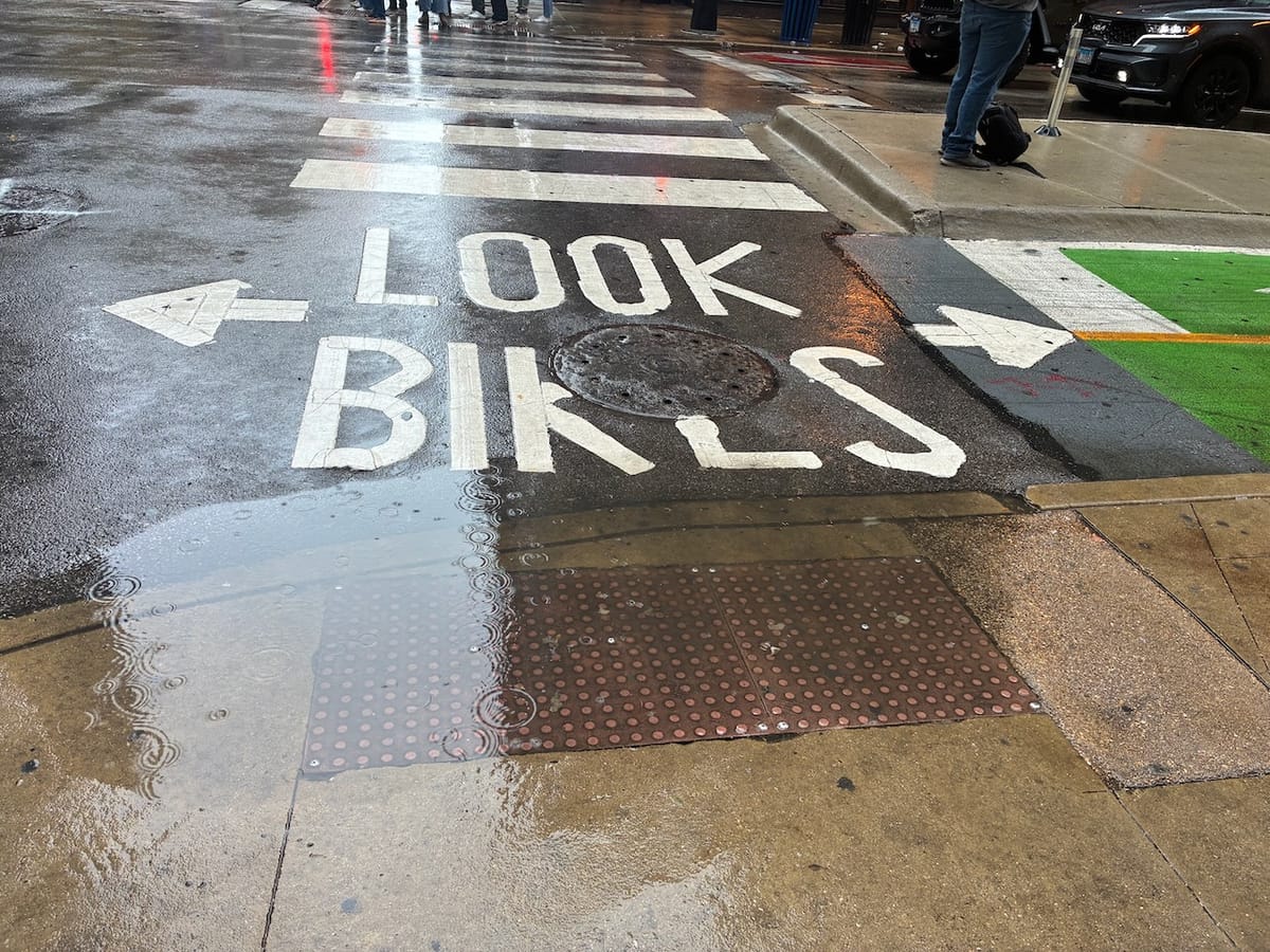 Road markings at a crosswalk that says "Look Bikes" with arrows going in both directions to indicate there is a two-way bicycle cross-traffic to look for.