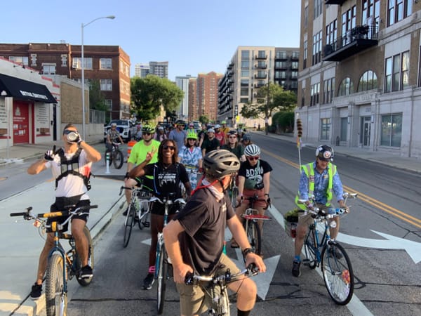 Large group of happy cyclists stopped on Van Buren Street in Milwaukee