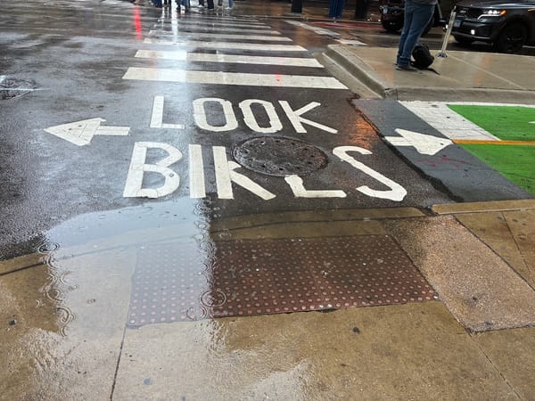 Road markings at a crosswalk that says "Look Bikes" with arrows going in both directions to indicate there is a two-way bicycle cross-traffic to look for.